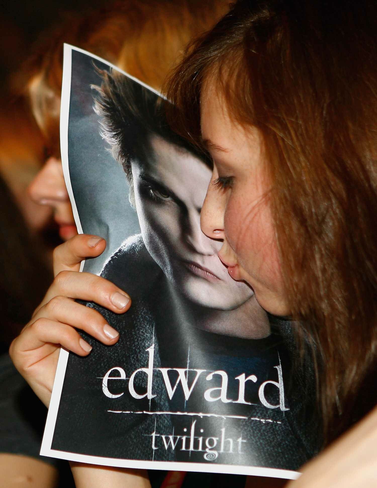 female fan kisses a poster showing the face of actor Robert Pattinson