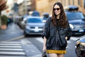 A woman wears an oversized leather jacket over a mini skirt