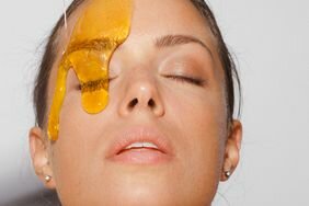 Woman putting honey on her skin for added skincare benefits