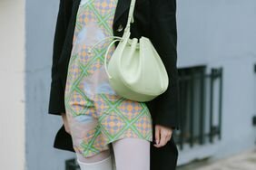 A woman wears a green bag designed by Mansur Gavriel, a brand that makes vegan leather bags.