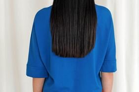 The back-view of a person with long, straight brown hair who is wearing a blue shirt