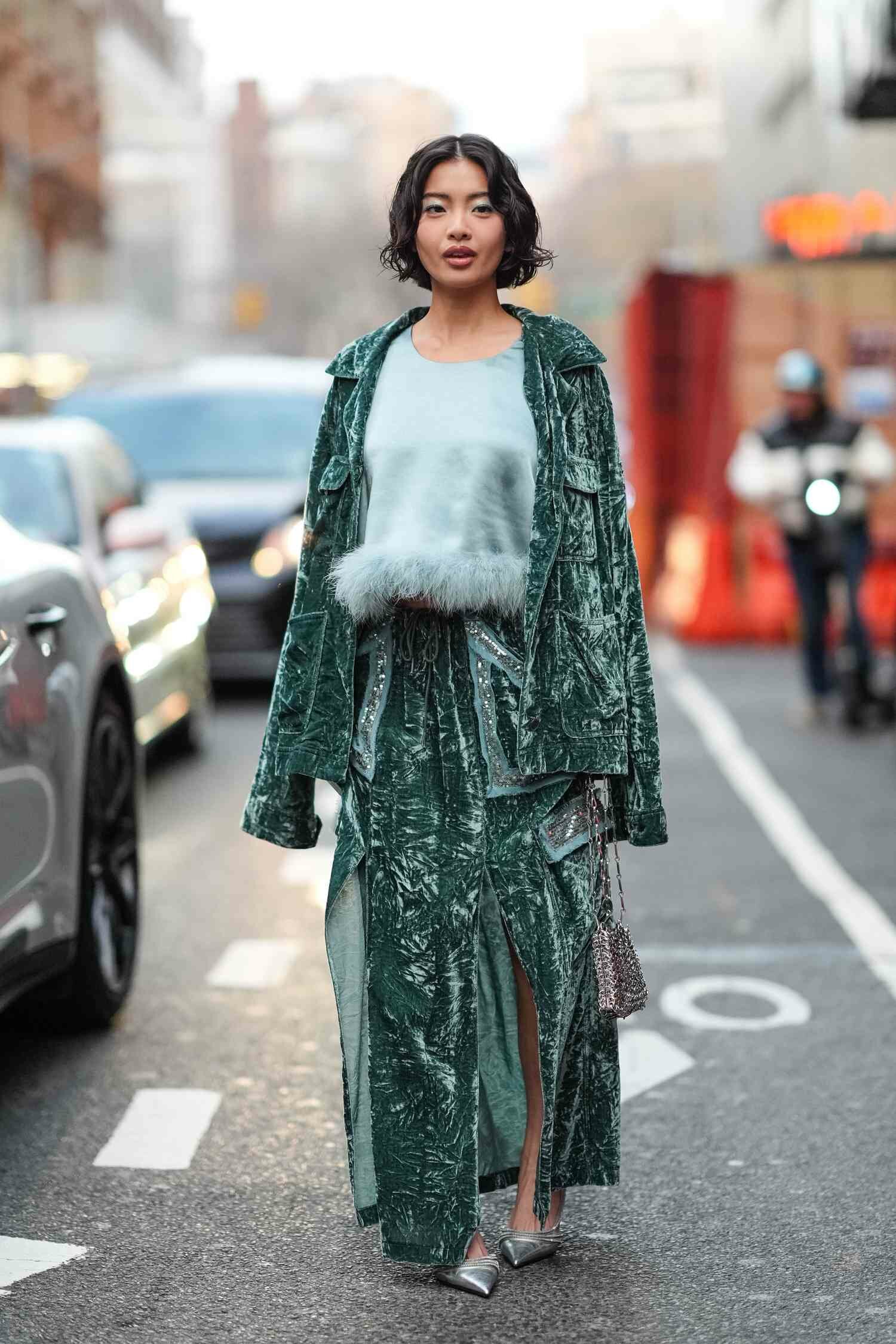 A NYFW guest wears a green Anna Sui outfit during New York Fashion Week.