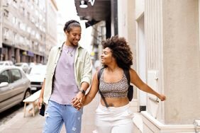 Happy Black couple hold hands walking down the street
