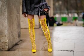 Wearing yellow lace-up thigh-high boots, a woman show show to wear over-the-knee boots with a leather mini skirt.