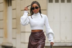 Person wears a winter outfit of cropped white knit and brown leather skirt