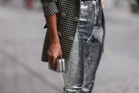 A woman wears sparkly silver sequin pants, a style of fun pant that is part of the fun pants trend.
