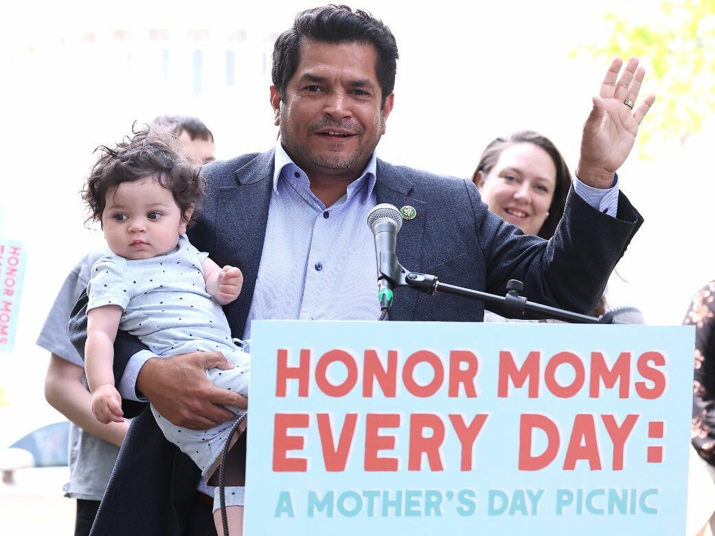 Rep. Jimmy Gomez (D-CA) at a MomsRising rally for paid leave, holding his child.