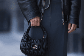 A woman carried a black, ruched Miu Miu handbag, a type of handbag.