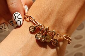 A woman wears a zodiac jewelry charm bracelet from Rellery Jewelry.