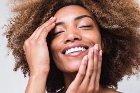 african american woman with natural hair touching her face and smiling