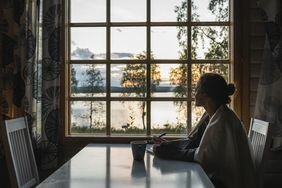Person sitting at kitchen table looking out window at lake