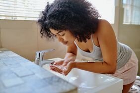 Shot of a beautiful young woman washing her face in the bathroom - stock photo
